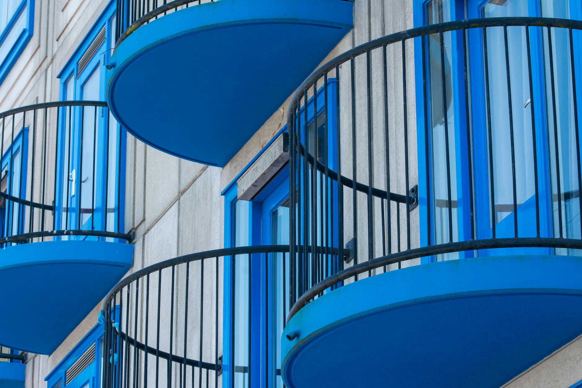 Zbliżenie nowoczesnej elewacji z niebieskimi stalowymi balustradami balkonu