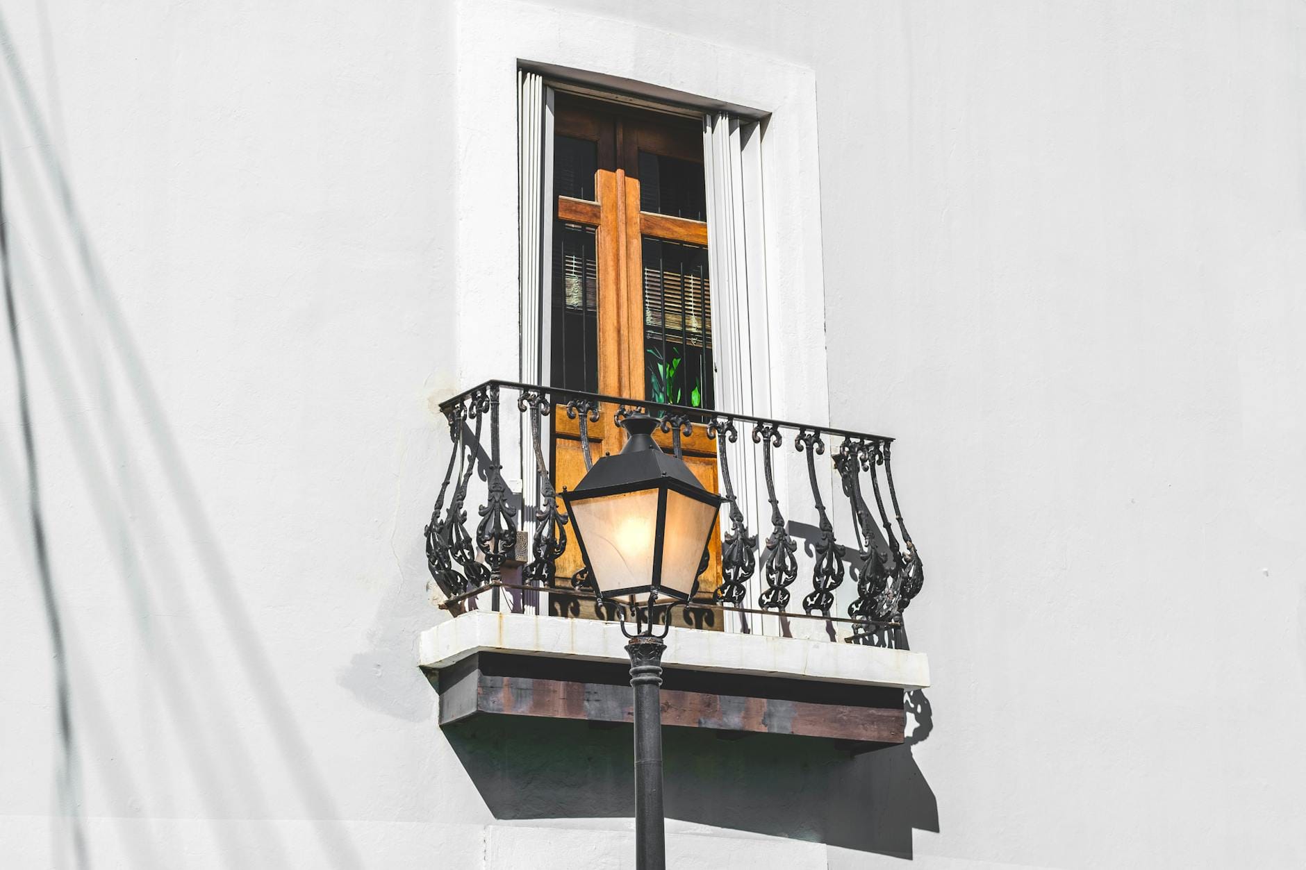 Balkon z ozdobną metalową balustradą na białej elewacji budynku