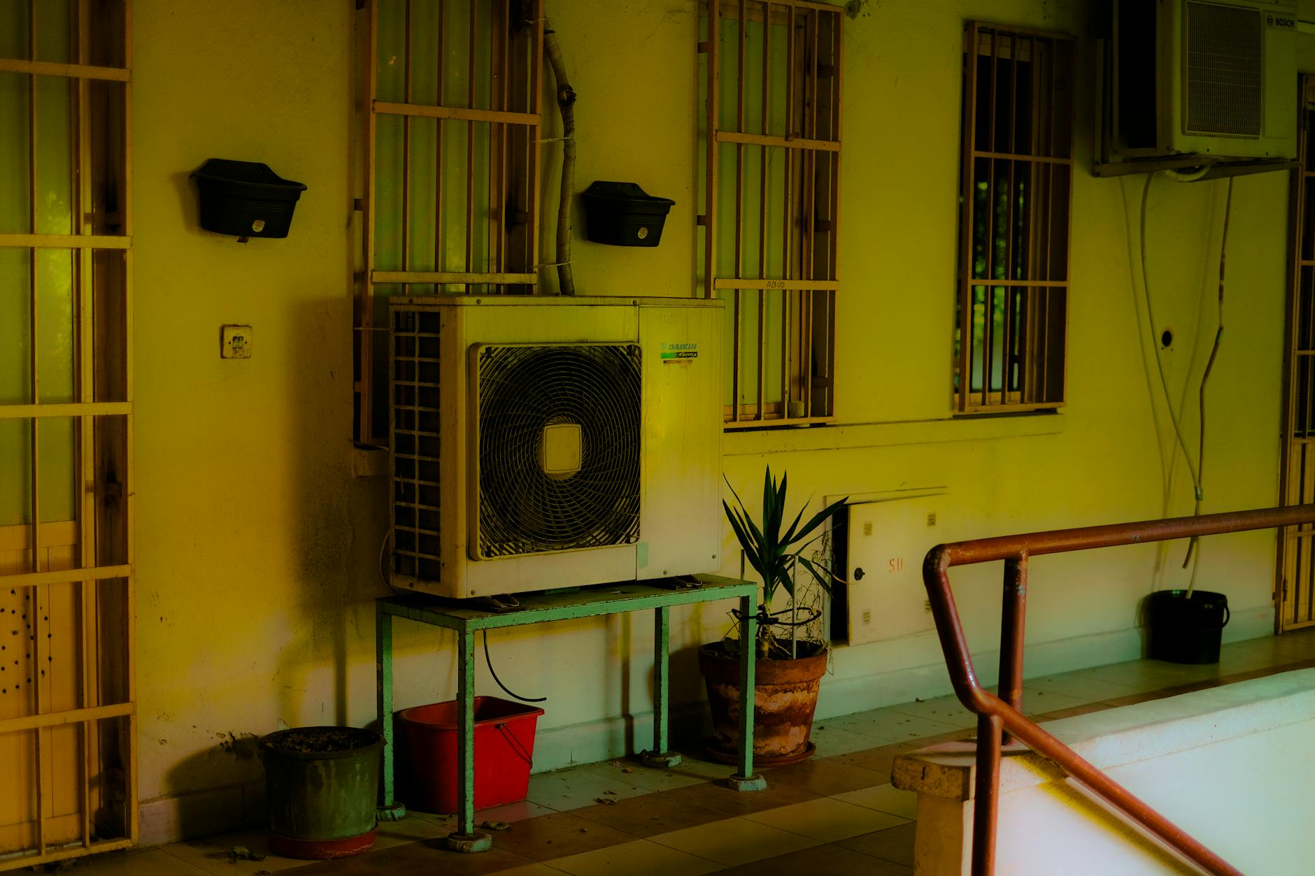 Klimatyzator na balkonie z doniczkami w miejskiej zabudowie