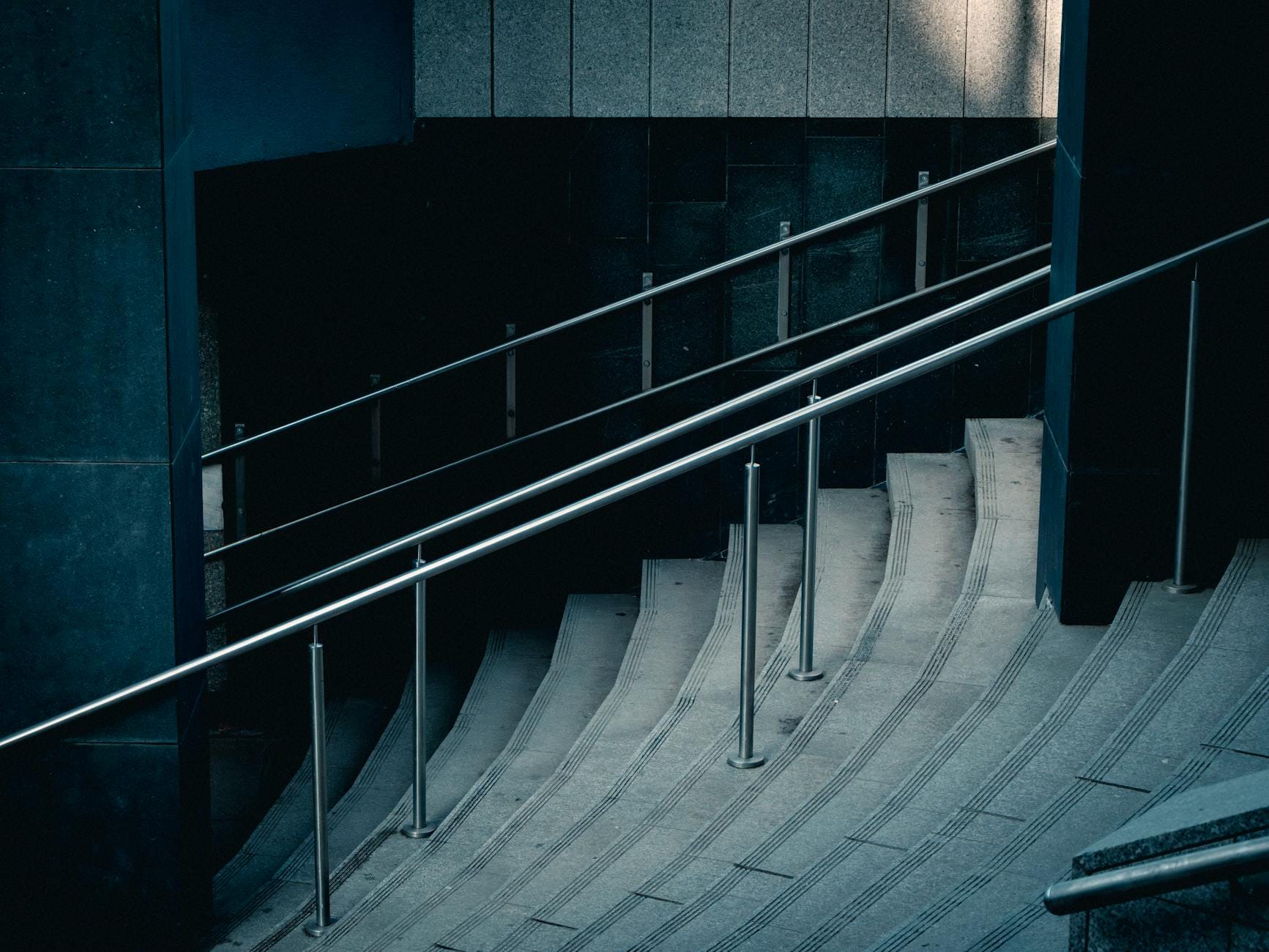 Kręte betonowe schody z nowoczesną metalową balustradą w budynku