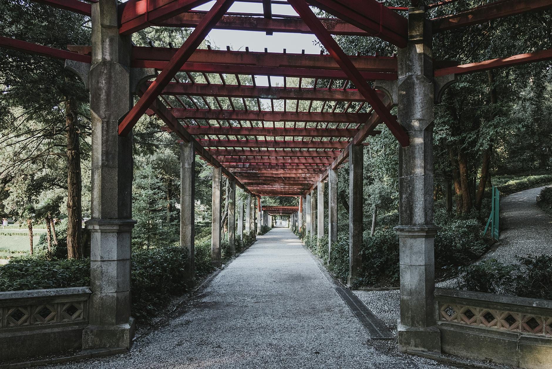 Rustykalna pergola ogrodowa przy ścieżce wśród bujonej zieleni