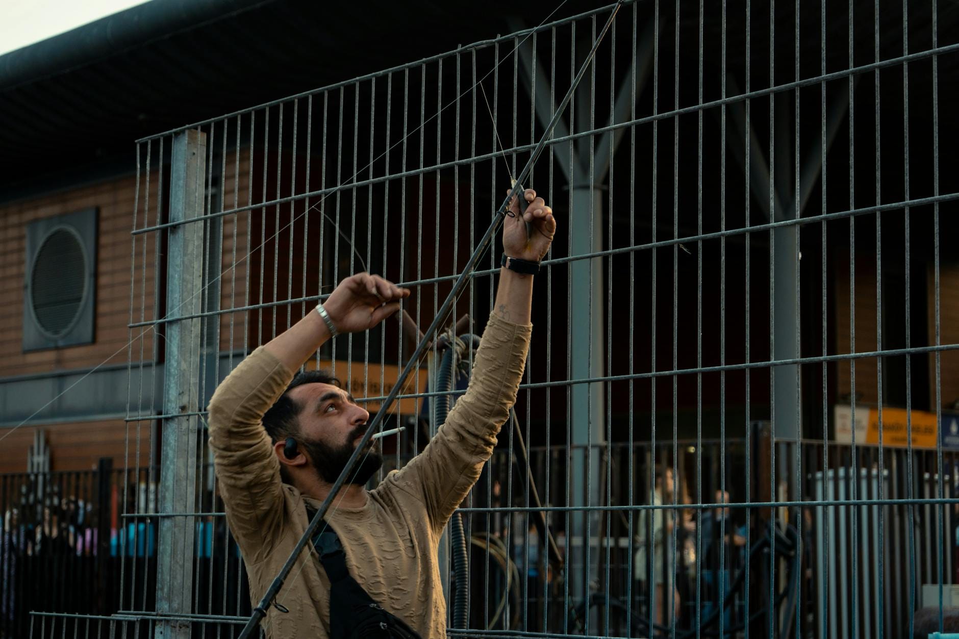 Mężczyzna serwisujący metalowe ogrodzenie na zewnątrz za dnia