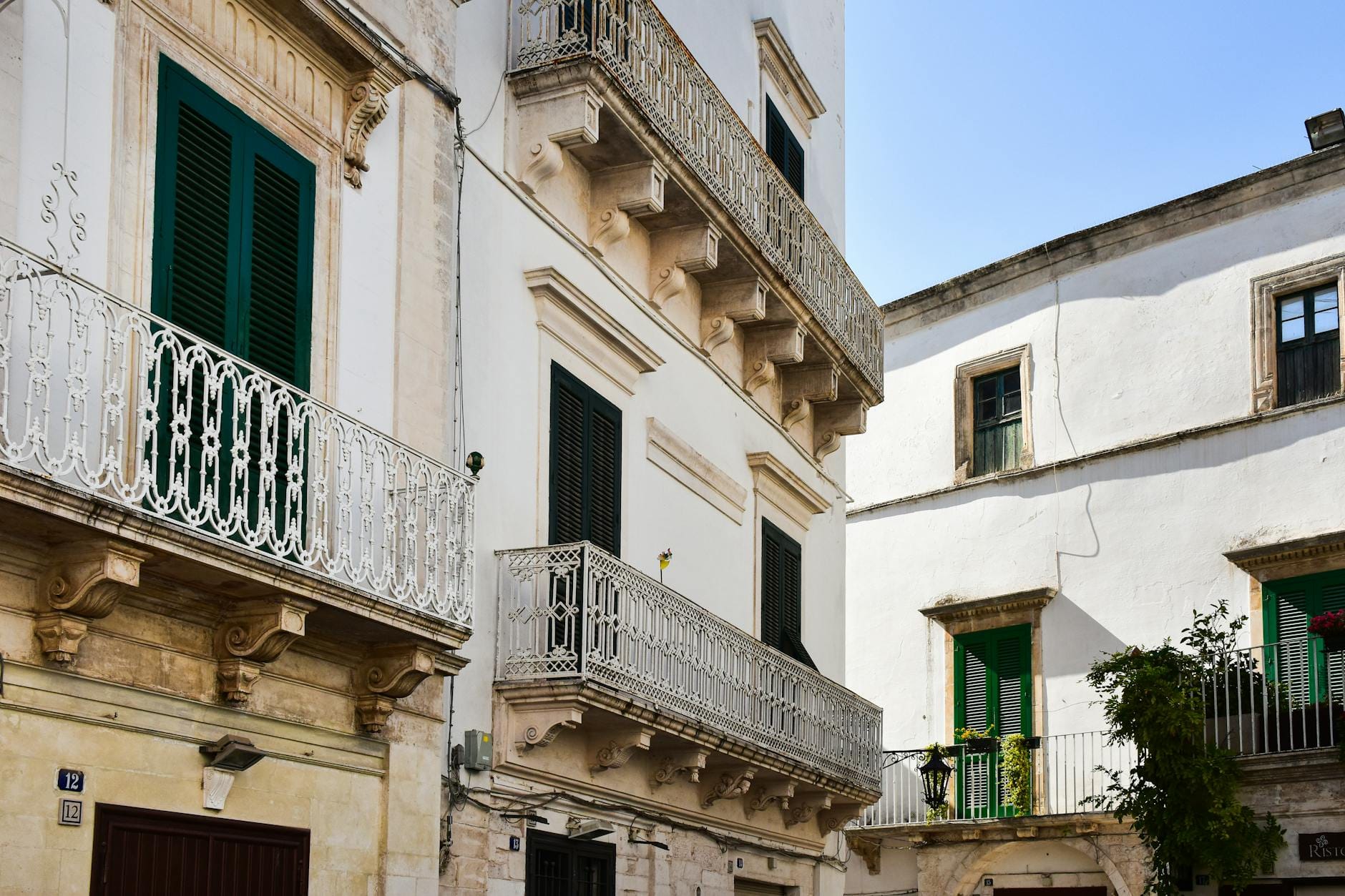 Słoneczna ulica we Włoszech z białymi kamienicami i zdobionymi balkonami Słoneczna ulica we Włoszech z białymi kamienicami i zdobionymi balkonami