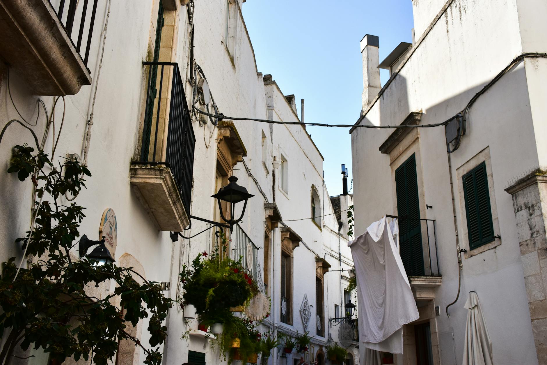 Wąska uliczka w Lecce z bielonymi kamienicami i kwiatami na balkonach